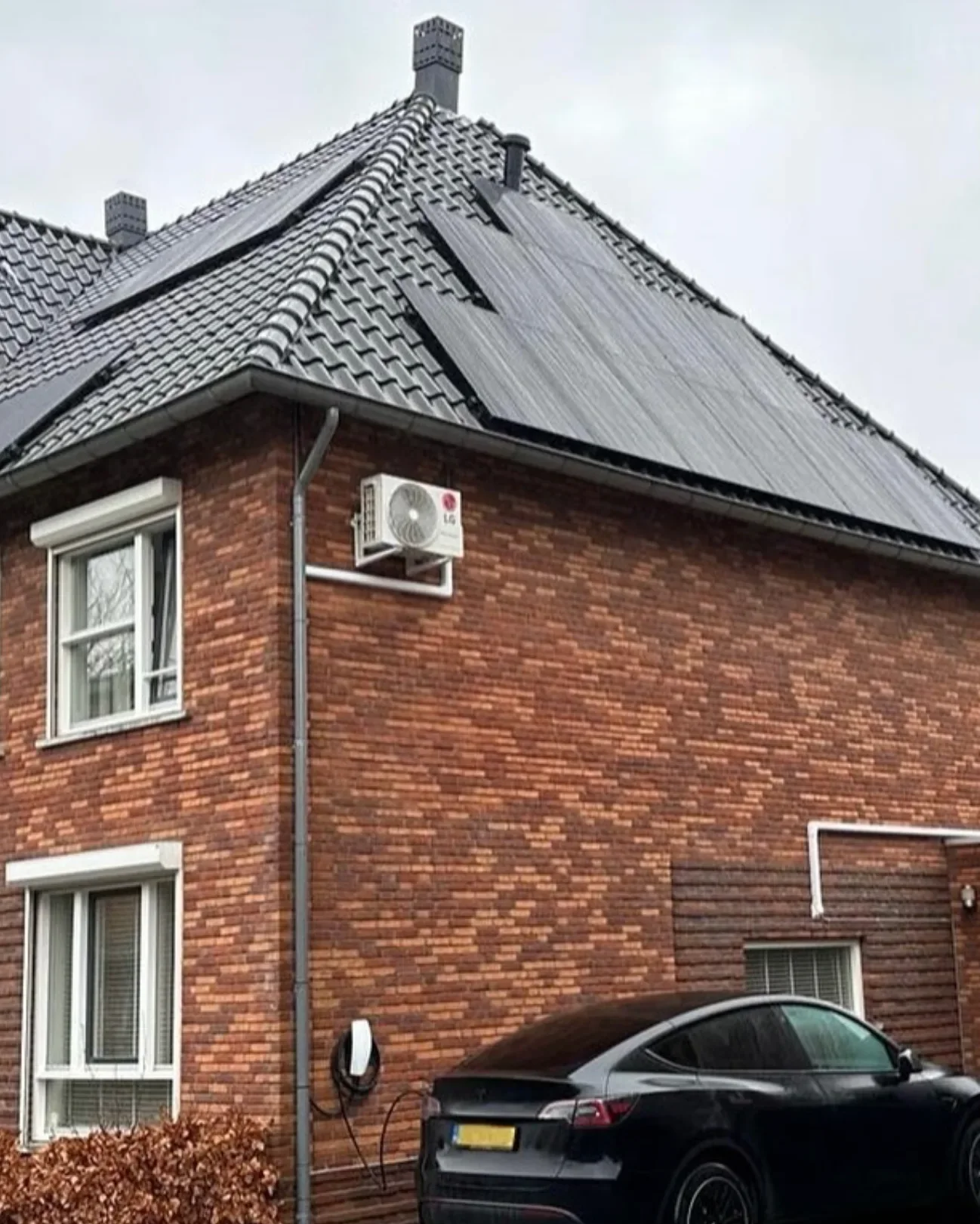 Woning met zonnepanelen op het dak en een elektrische auto aan de laadpaal